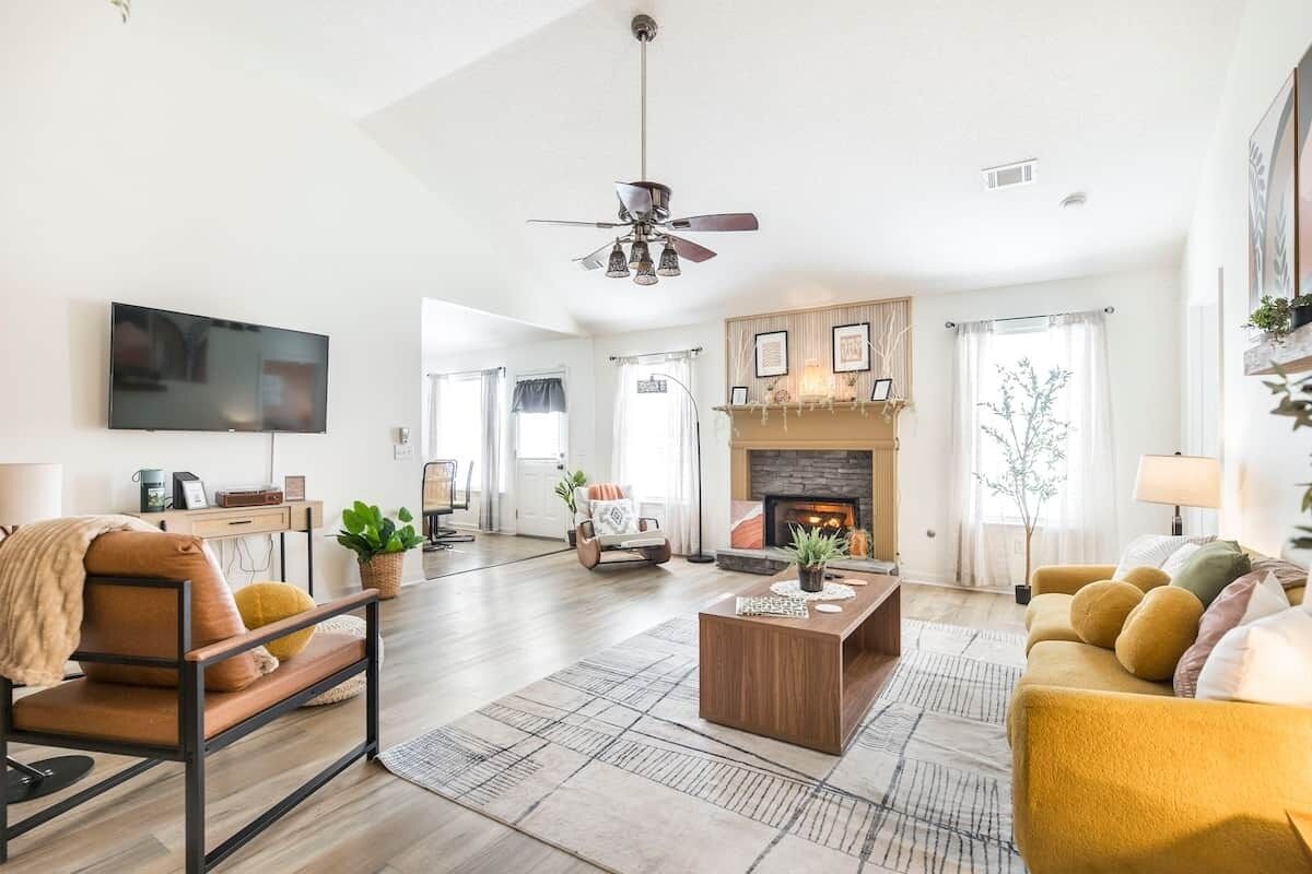 A living room with a fireplace, a ceiling fan, a TV, and a sofa.