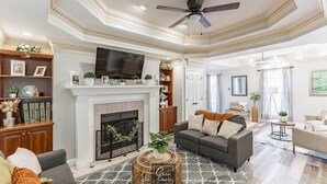 A living room with a fireplace, a ceiling fan, and a television mounted above it. - Spacious 3BR 3BA 5 bds Decatur Townhouse (Decatur)