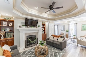 A living room with a fireplace, a ceiling fan, and a television mounted above it. - Spacious 3BR 3BA 5 bds Decatur Townhouse (Decatur)