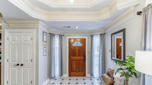 A hallway with a wooden door, white walls, a tiled floor, and a plant. - Spacious 3BR 3BA 5 bds Decatur Townhouse (Decatur)