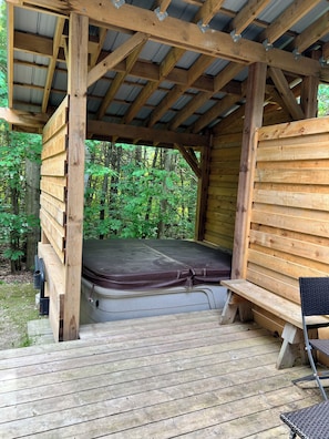 Eine Holzhütte mit erhöhter Plattform, einer Matratze und einer Bank.