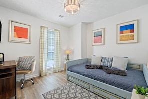 A bedroom with a bed, a desk, a chair, and a window with curtains. - Urban CasaOasis 5BR4BA Retreat Theatre & Game (Gwinnett County)