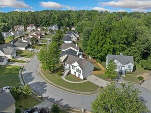 A residential area with houses, a curved road, and a forested hill in the background. - Urban CasaOasis 5BR4BA Retreat Theatre & Game (Gwinnett County)