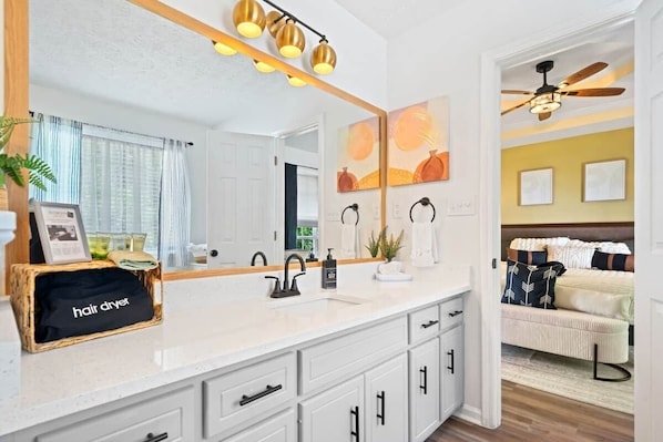 A bathroom with a white vanity, a hair dryer, and a ceiling fan. - Urban CasaOasis 5BR4BA Retreat Theatre & Game (Gwinnett County)