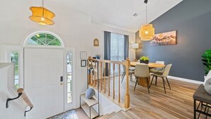 Een modern interieur met een trap, een eethoek en kunstwerken aan de muur.