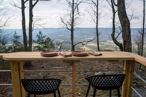 Ein Holztisch mit zwei Stühlen, gedeckt für zwei Personen, mit Blick auf eine schöne Landschaft.
