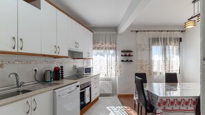 Una cucina con mobili bianchi, un forno a microonde, un bollitore e un tavolo da pranzo con sedie.