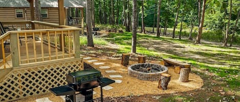 A wooden deck with a grill and propane tank, a fire pit, and a covered seating area.
