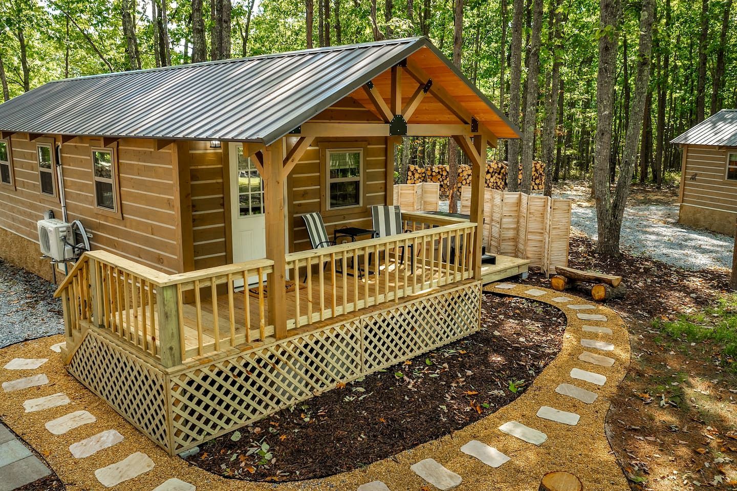 A cabin with a deck, a covered porch, and a small outdoor seating area.
