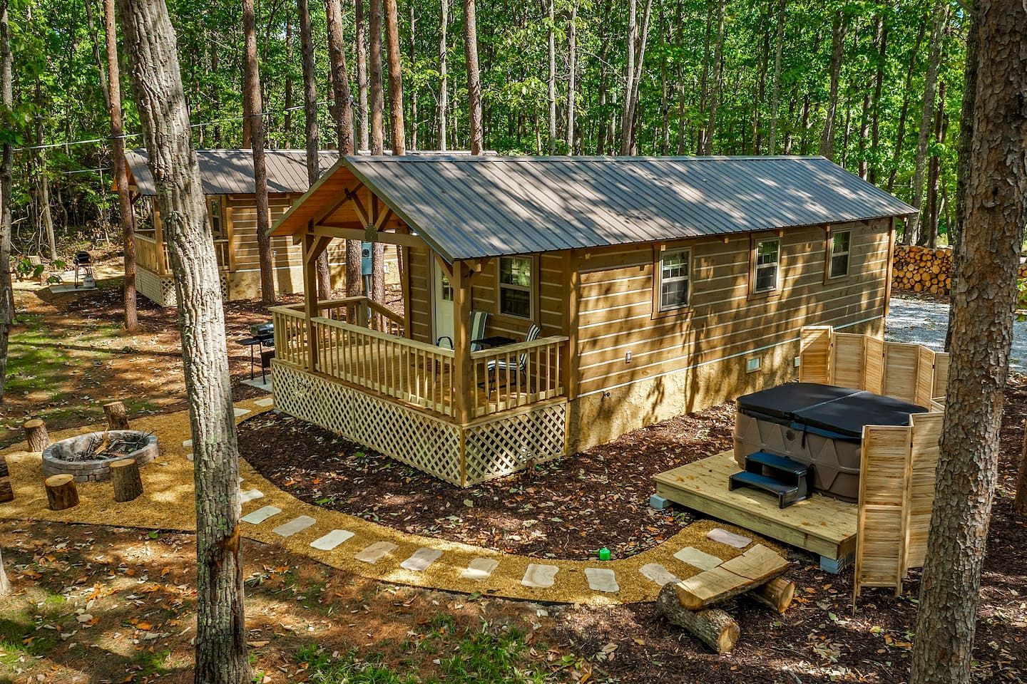 Une cabane en bois dotée d’une terrasse, d’un foyer extérieur et d’un espace salon extérieur abrité.