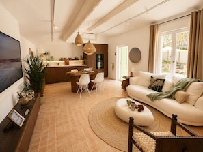 Ein modernes Wohnzimmer mit Fernseher, Sofa und Essbereich.
