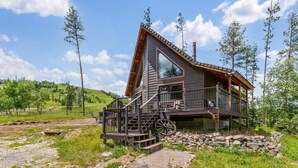 Une cabane en bois avec un toit à forte pente, une véranda et des fondations en pierre.