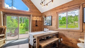 L’intérieur d’un chalet en bois, avec une table, un banc et deux chaises.
