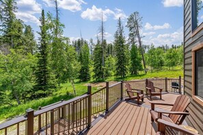 A wooden deck with chairs, surrounded by a forest. - Elk Pointe Chalet- Hot Tub and Views! (Lead)