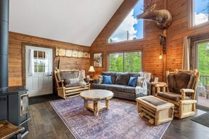 A log cabin interior with a fireplace, wooden furniture, and a deer head mounted on the wall. - Elk Pointe Chalet- Hot Tub and Views! (Lead)