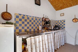 A kitchen with a checkered backsplash, hanging pots, and a stove.