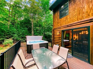 Eine Holzhütte mit Whirlpool, Glastisch und Stühlen auf einer Außenterrasse.