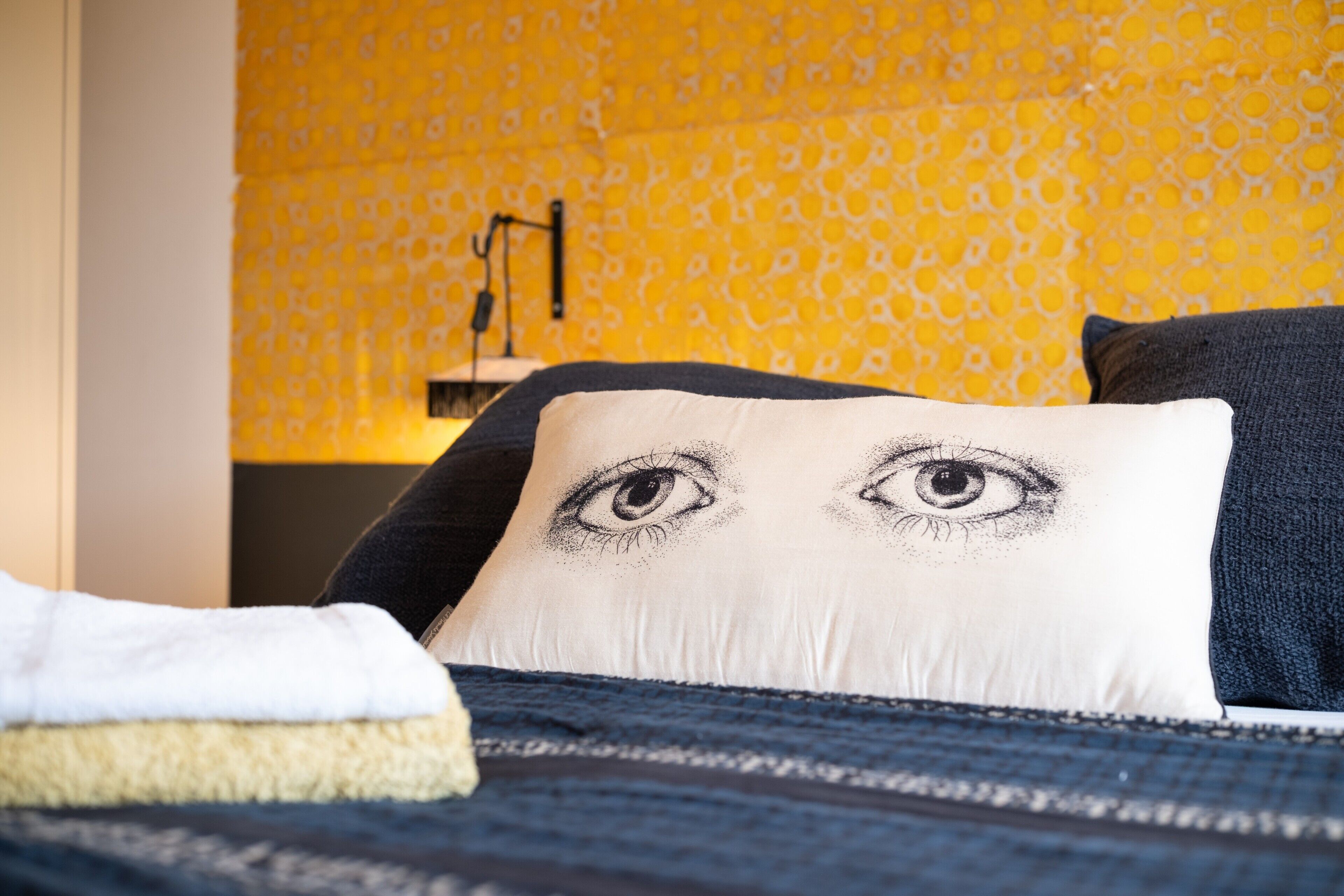 A bed with a patterned wall in the background.