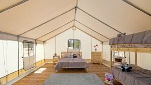 A tented accommodation with a single bed, a bunk bed, a small table, and a window. - Adventure Tent in Boerne, TX (Boerne)