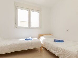 A room with two single beds, a window with blinds, and a light switch on the wall. - Benicarlo Center by Interhome (Benicarló)