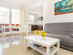 A modern living room with a grey sofa, white coffee table with flowers, and a dining area with white chairs. - Benicarlo Center by Interhome (Benicarló)