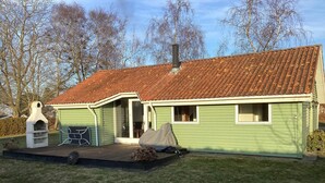 A green house with a tiled roof, a barbecue grill, and a chimney. - 4 Star Holiday Home in Stubbekobing (Stubbekobing)