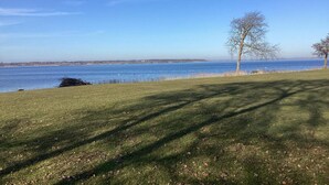 A grassy area with a clear view of a body of water and distant land. - 4 Star Holiday Home in Stubbekobing (Stubbekobing)
