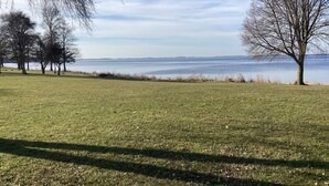 A grassy field with trees and a body of water in the background. - 4 Star Holiday Home in Stubbekobing (Stubbekobing)