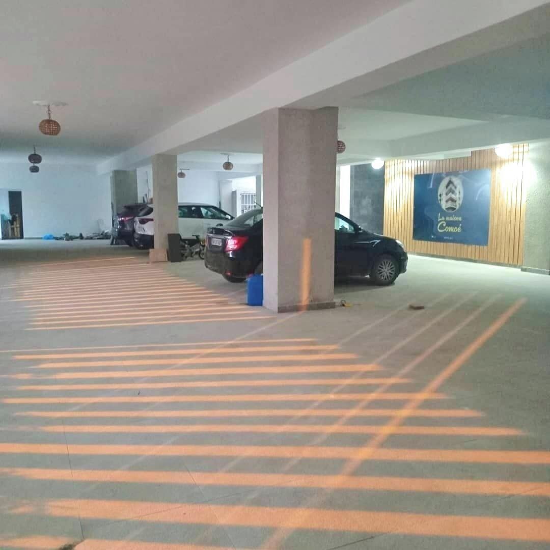 A parking garage with concrete pillars, marked parking spaces, and a few cars parked.