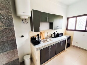 A modern kitchen with a granite countertop, dark cabinets, a sink, and a window providing natural light.