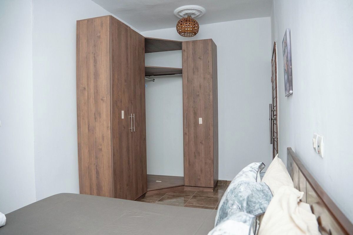 Un dormitorio con cama, armario de madera y lámpara en el techo.
