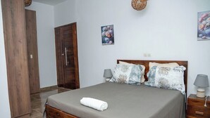 Ein Schlafzimmer mit einem hölzernen Bett, zwei Nachttischen, einer Tür und zwei an der Wand befestigten Bildern.
