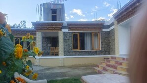 A two-story house with a stone facade, a balcony, and a small porch. - Rabgais Nubra Retreat (Hunder)