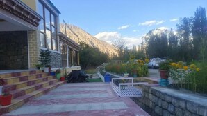 Un bâtiment doté d’une façade en pierre, d’un porche abrité et d’un chemin pavé menant à la montagne.