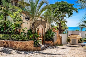 Ein Gebäude mit einer Steinauffachung, einem Schild mit der Aufschrift 'La Villa Linda' und Blick auf das Meer.