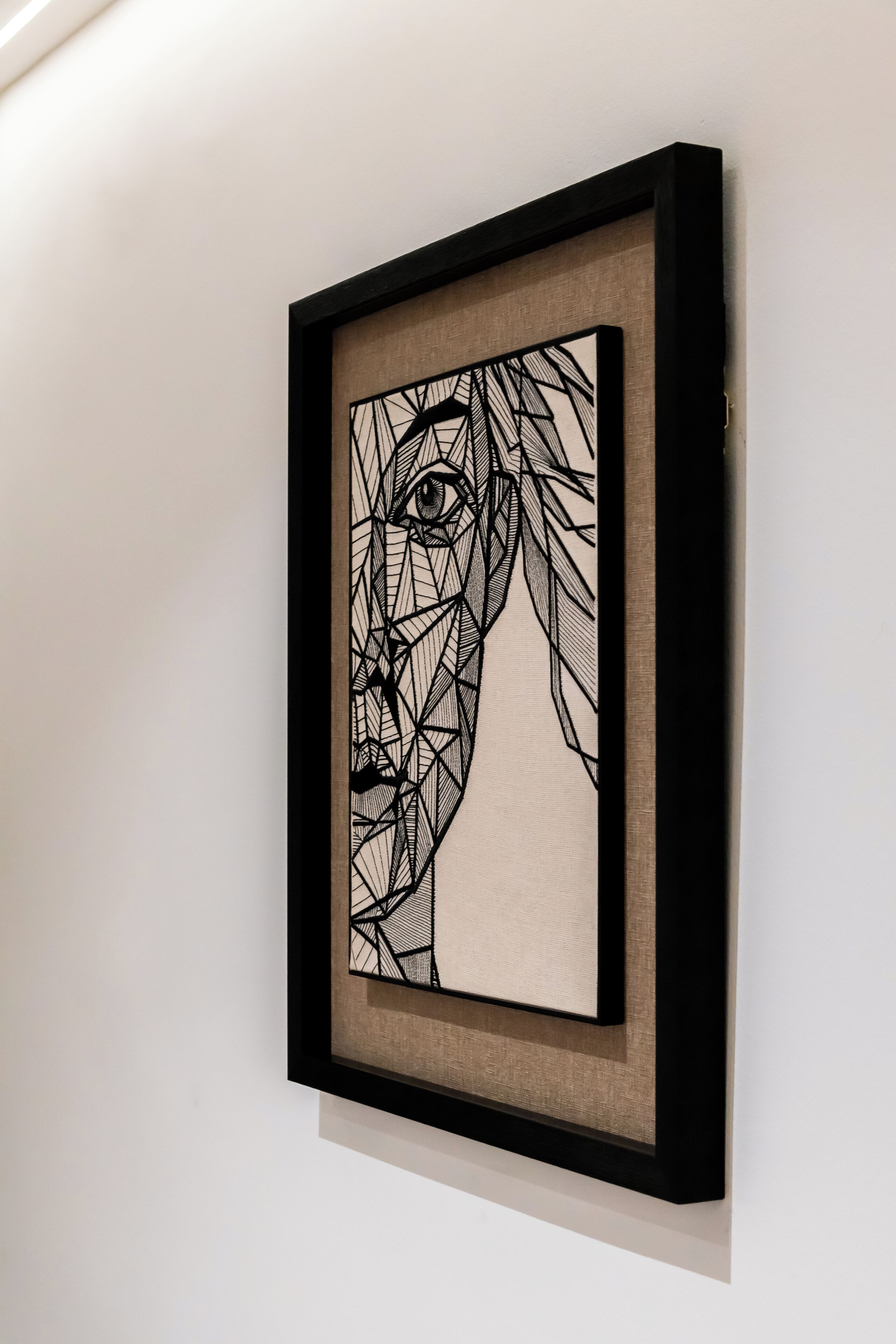 A framed artwork with geometric patterns on a wall.