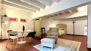 A room with a bed, a chair, a table, a lamp, and a rug. - Santo Spirito Cute Loft (Firenze)