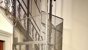 A metal stairwell with a mesh enclosure, a door with a lock, and a handrail. - Santo Spirito Cute Loft (Firenze)
