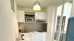 A compact kitchen with a built-in oven, a kettle, and a refrigerator. - Santo Spirito Cute Loft (Firenze)