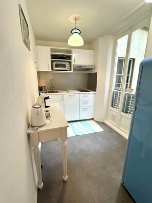 A compact kitchen with a built-in oven, a kettle, and a refrigerator. - Santo Spirito Cute Loft (Firenze)