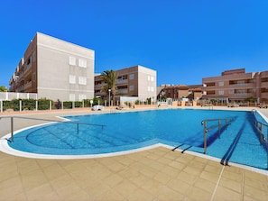 A swimming pool with a tiled deck, surrounded by multi-story buildings with balconies. - Kris Costasol by Interhome (Costa del Silencio)