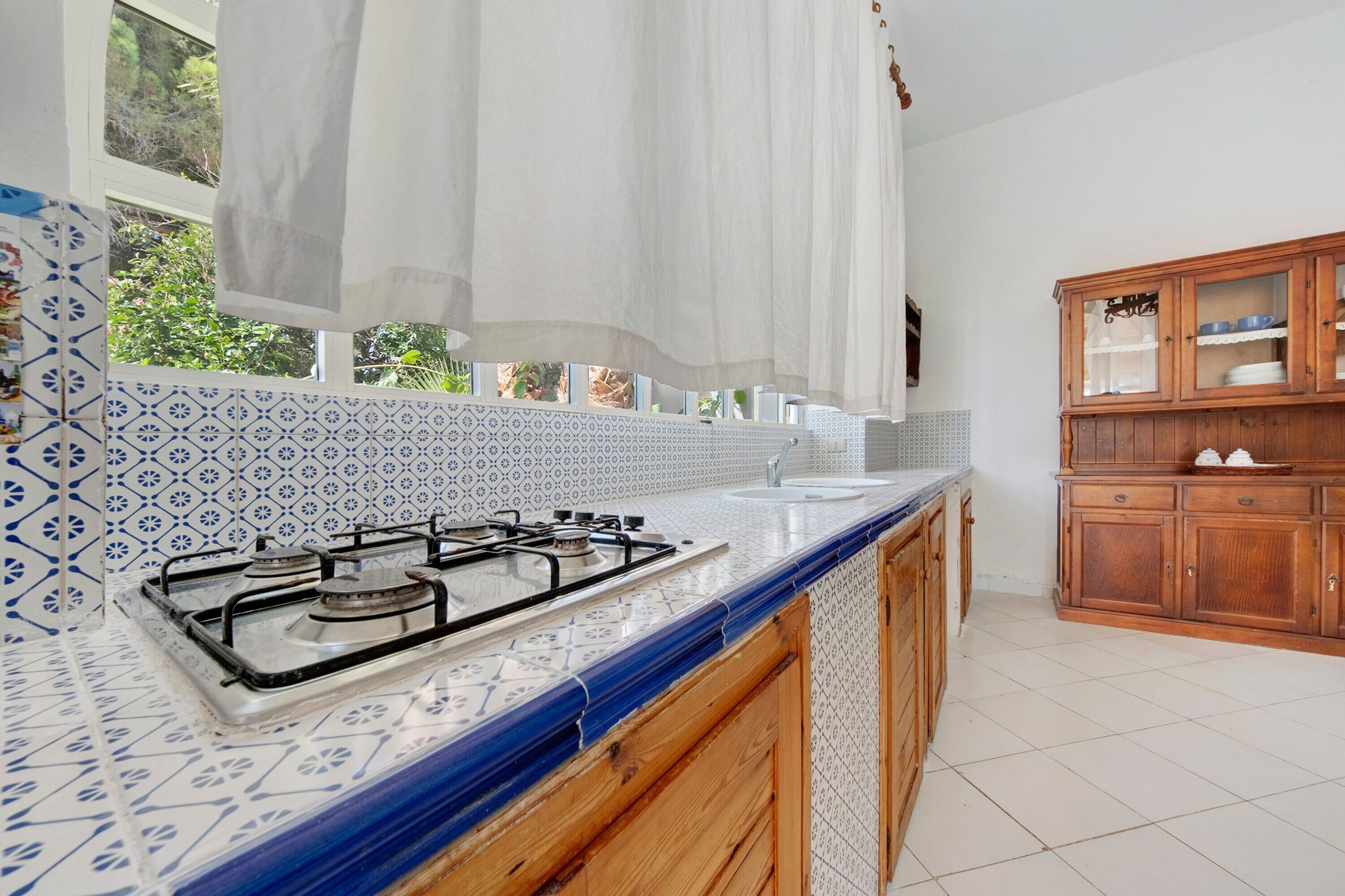 A kitchen with a gas stove, a sink, and a wooden cabinet.
