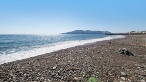 A pebbly beach with a clear sky and a distant mountain.