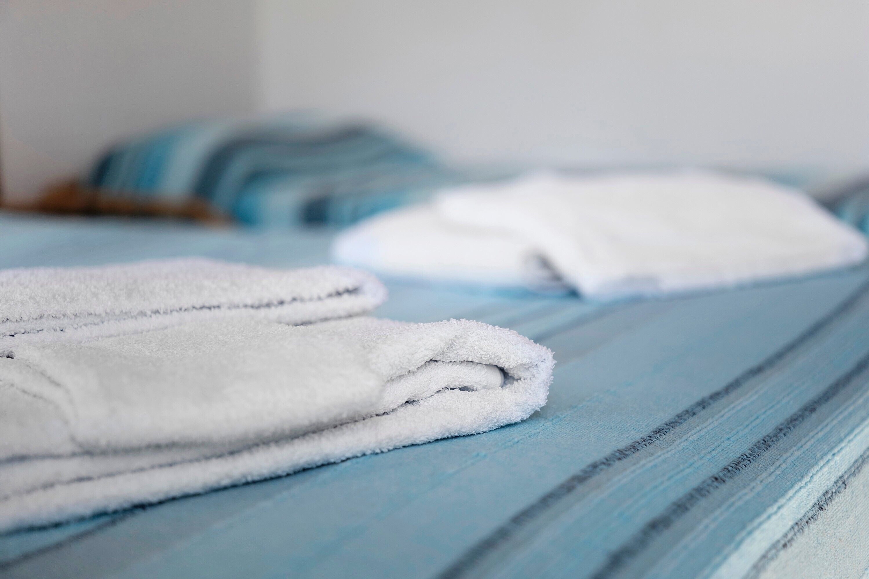 Un letto rifatto con asciugamani bianchi e una coperta a righe blu.