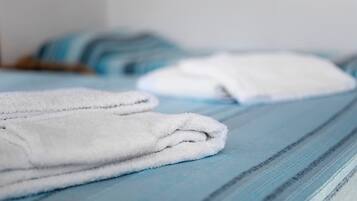 Un letto rifatto con asciugamani bianchi e una coperta a righe blu.