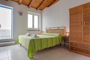 Ein Schlafzimmer mit Bett, Fenster, Kleiderschrank und Nachttischlampe.