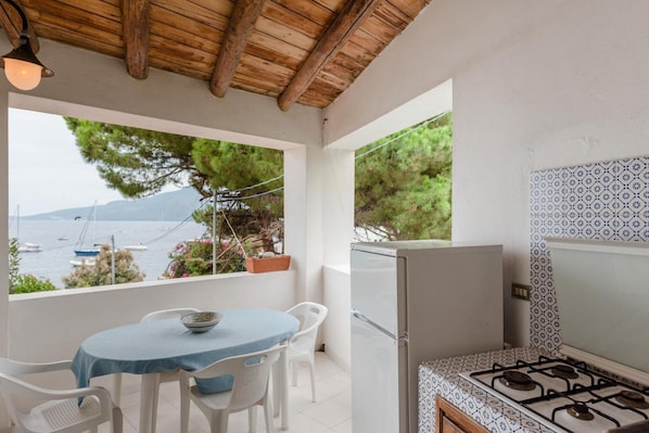 A kitchen with a gas stove, a refrigerator, and a dining area with a table and chairs. - Apartment 'Quadara - Sul Rifugio' with Sea View, Private Terrace and Shared Garden (Lingua)