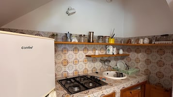 Een koelkast, een kookplaat, kookgerei, borden en bestek