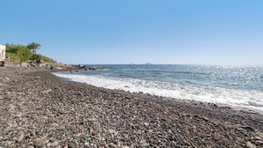 A pebbled beach with a clear sky and calm sea.