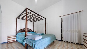 A four-poster bed with a wooden frame, a matching nightstand, and a patterned floor.